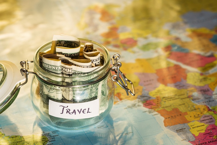 Money saved in a jar for your travel plan, on a map